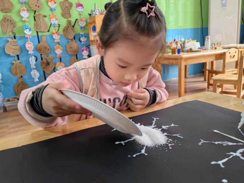 图一：2023年11月17日，聊城高新区天津路实验幼儿园开展班级区域《盐画雪花》活动，小朋友们在往雪花上撒盐。.jpg